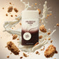 Une photo haute vitesse figée au format carré de 1200x1200px. Le flacon de parfum d'image_936c05.jpg est le point focal absolu au centre. Autour de lui, de fines vagues de crème lactée et des brisures de biscuits croquants volent dynamiquement dans l'air, créant un effet de mouvement suspendu. L'arrière-plan présente un dégradé très doux allant du blanc crème au brun chaud. (gpt-image-2)